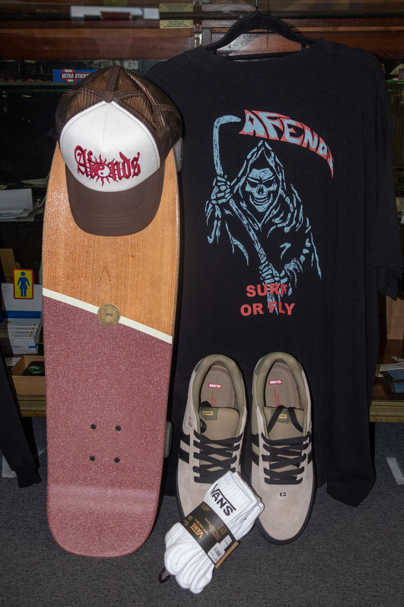 Skate deck, cap, tee and shoes laid out in store.